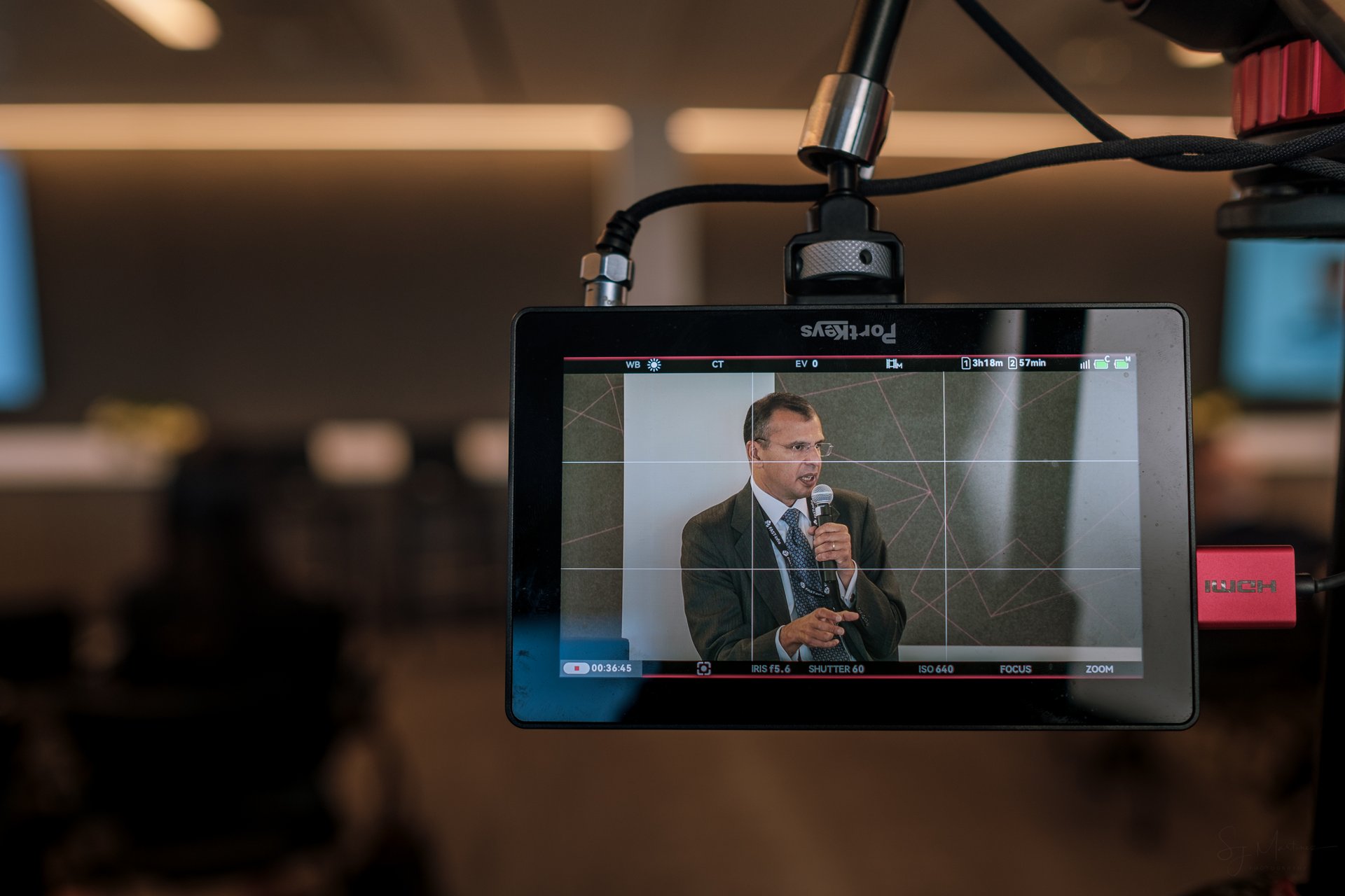 Camera monitor showing a live feed of a speaker at a podium