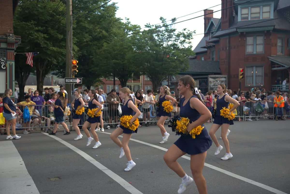 Cheerleaders performing in a community parade along a street
