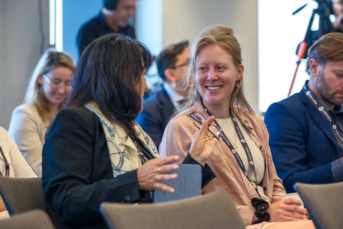 Smiling attendees seated at a conference wearing lanyards