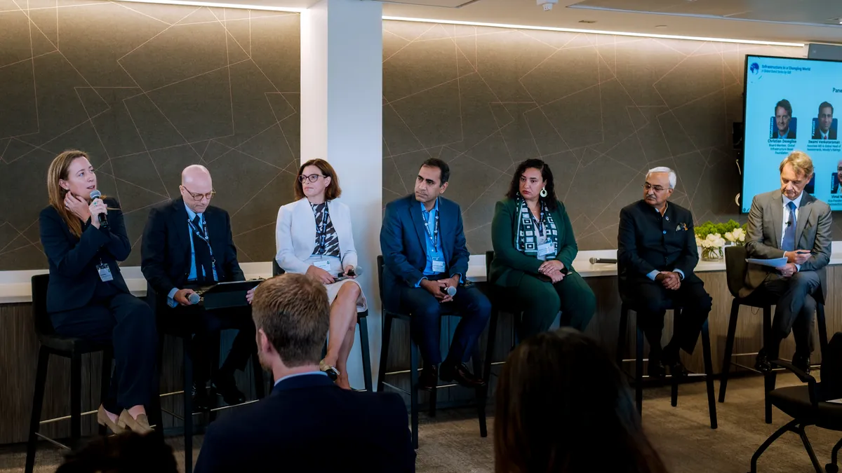 Panel of speakers seated on a stage with audience members in the foreground