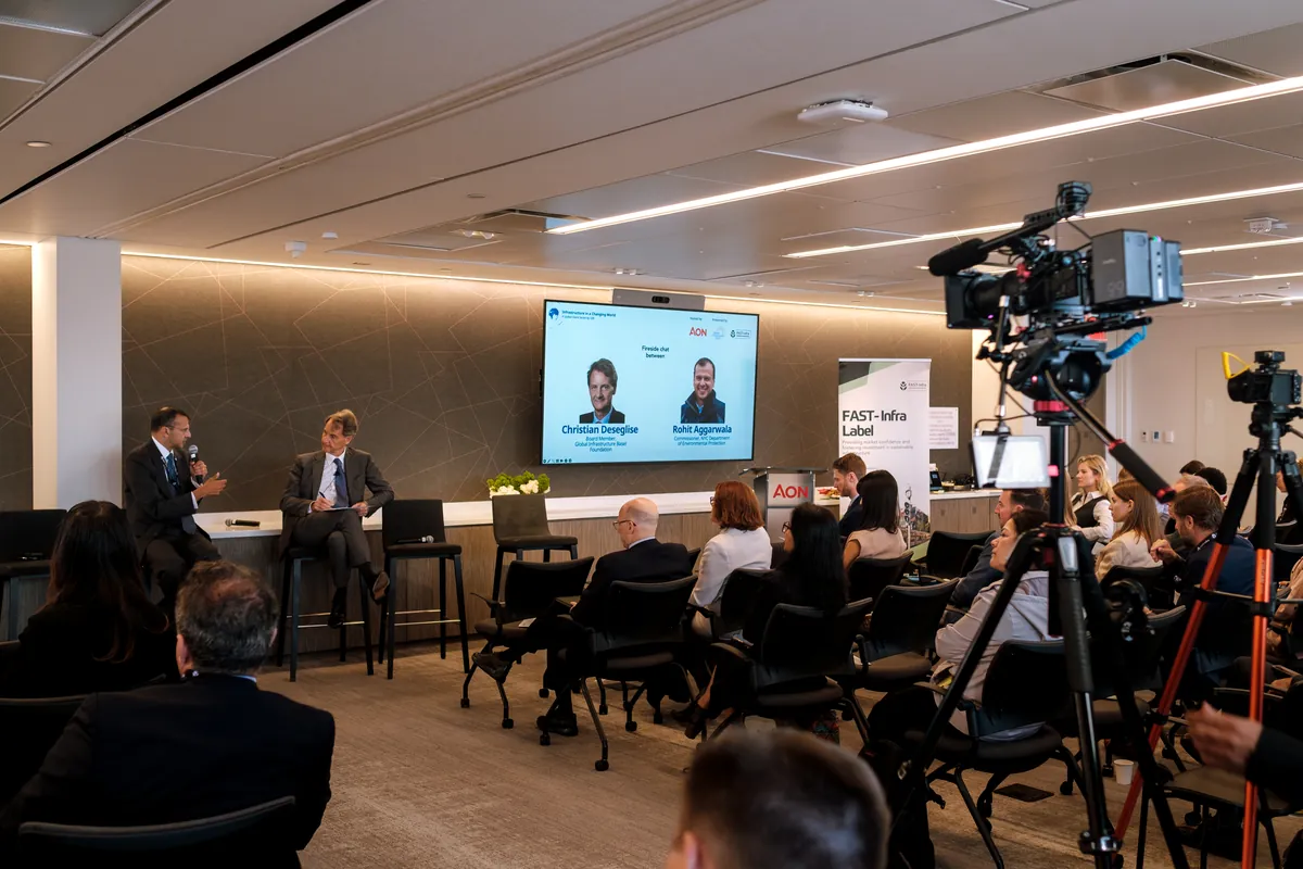 Video camera on a tripod filming a panel in a large event venue