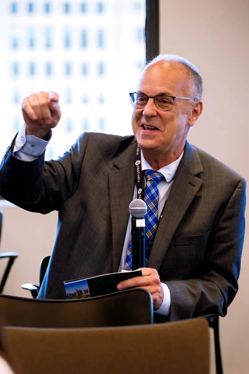 Speaker with a lapel microphone raising his fist at a podium